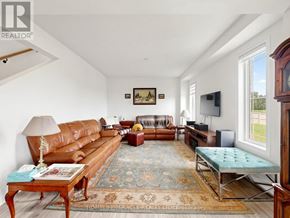 Wasaga Beach apartment for rent - A living room with a brown leather sofa, a wooden coffee table, a blue ottoman, and a rug with a floral pattern.