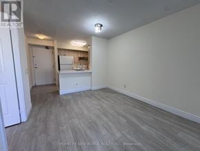 Toronto (Lansing-Westgate) condo for rent - A room with a white door and a small kitchenette in the background.