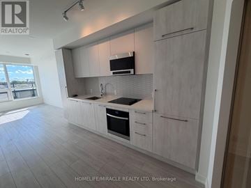 Mississauga (Lakeview) condo for rent - A modern kitchen with white cabinets and a black stove top oven.
