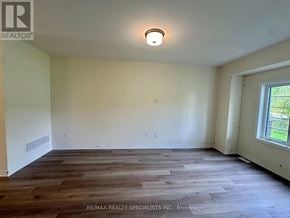 Brant (Brantford Twp) townhouse for rent - A room with wooden flooring and a window showing greenery outside.