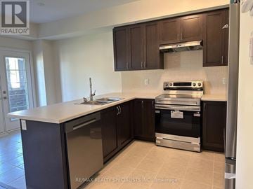 Brant (Brantford Twp) townhouse for rent - A kitchen with a stove top oven and a refrigerator.