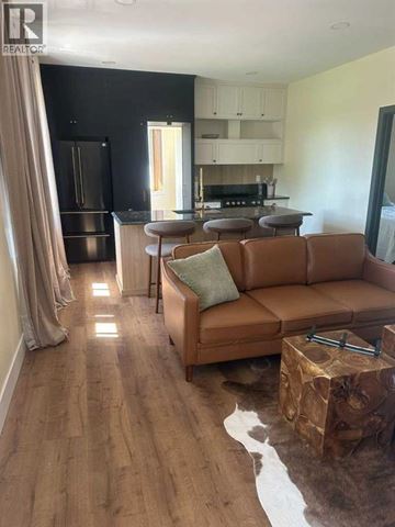 Blairmore apartment for rent - A living room with a brown leather couch and a cowhide rug.