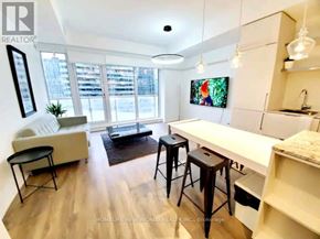 Toronto (Church-Yonge Corridor) condo for rent - A living room with a white couch, a black chair, and a TV mounted on the wall.