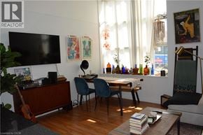 Kitchener condo for rent - A living room with a wooden floor and a large window with white curtains.