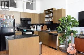 Kitchener condo for rent - A kitchen with a black fridge, black countertops, and wooden cabinets.