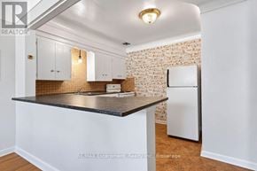 Burlington (Brant) multi-family for rent - A kitchen with white cabinets and a brick wall.