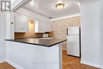 Burlington (Brant) multi-family for rent - A kitchen with white cabinets and a brick wall.