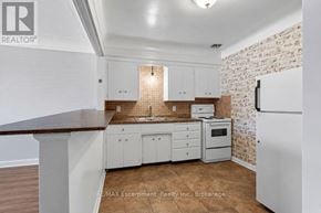 Burlington (Brant) multi-family for rent - A kitchen with white cabinets and a brick wall.