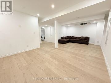 Brampton (Bram East) apartment for rent - A spacious living room with a brown couch and wooden flooring.