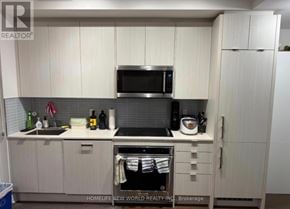 Toronto (Annex) condo for rent - A kitchen with white cabinets and a black microwave above the stove.