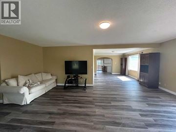 Rural Kneehill County apartment for rent - A living room with a white couch and a television.