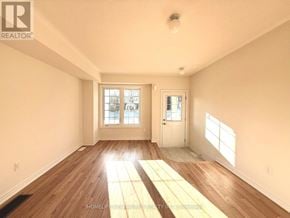 Pickering townhouse for rent - A sunny room with wooden floors and a large window.