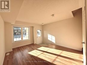 Pickering townhouse for rent - A room with wooden floors and white walls, with a window letting in sunlight.