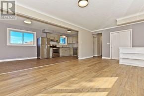 St. Catharines (Glendale/Glenridge) apartment for rent - A spacious room with wooden flooring and a kitchen area in the background.