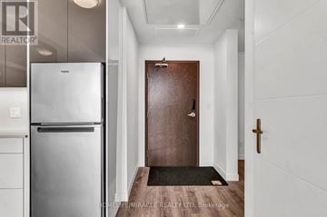 Kitchener condo for rent - A modern kitchen with a stainless steel refrigerator and a wooden door.