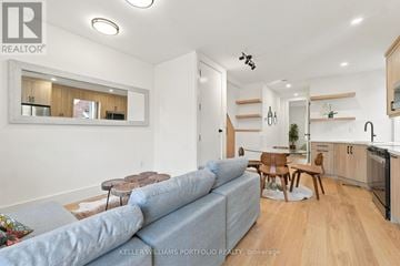 Toronto (Palmerston-Little Italy) duplex for rent - A living room with a grey couch and a kitchen area in the background.