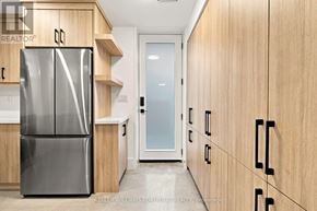 Toronto (Palmerston-Little Italy) duplex for rent - A modern kitchen with a stainless steel refrigerator and wooden cabinets.