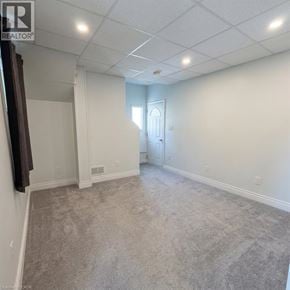 Kitchener apartment for rent - A spacious room with carpeted floor and white walls.