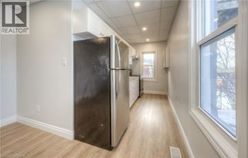 Kitchener apartment for rent - A kitchen with a black refrigerator and wooden floors.
