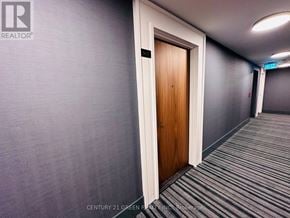 Brampton (Northwest Brampton) condo for rent - A hallway with a wooden door and grey carpeting.