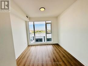 Brampton (Northwest Brampton) condo for rent - A room with wooden floors and a large window overlooking a cityscape.