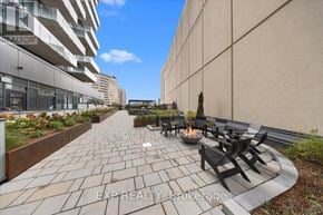 Ottawa condo for rent - A patio with a fire pit and chairs is surrounded by a wall and a building.