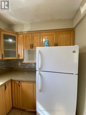 Mississauga (Malton) apartment for rent - A white refrigerator stands in a kitchen with wooden cabinets.