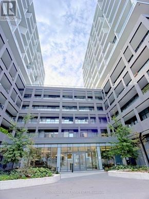 Toronto (Niagara) condo for rent - A modern building with a glass entrance and a courtyard in front.