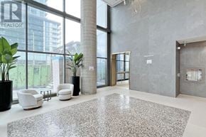 Vaughan (Vaughan Corporate Centre) condo for rent - A large, modern office lobby with a grey carpet and white furniture.