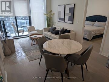 Oakville (Jm Joshua Meadows) condo for rent - A living room with a table and chairs in front of a large window.