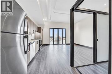 Hamilton condo for rent - A modern kitchen with a refrigerator on the left and a sliding glass door leading to a balcony.