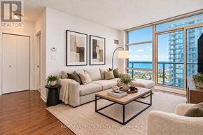 Toronto (Waterfront Communities) condo for rent - A living room with a large couch, a coffee table, and a view of the city.