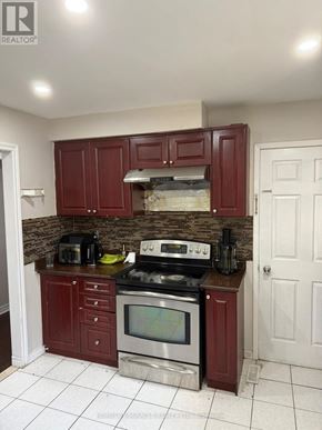 Toronto (West Humber-Clairville) apartment for rent - A kitchen with red cabinets and a brick backsplash.