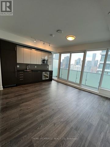 Toronto (Church-Yonge Corridor) condo for rent - A spacious kitchen with dark wood flooring and a city view through the windows.