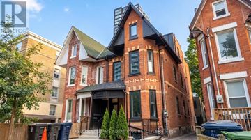 Toronto (Kensington-Chinatown) apartment for rent - A red brick house with a black roof and a sign that says "REAL ESTATE".