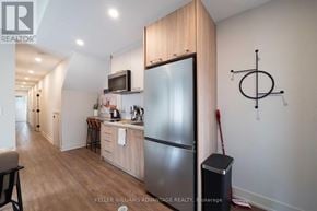 Toronto (Kensington-Chinatown) apartment for rent - A modern kitchen with a refrigerator, microwave, and a dining table.