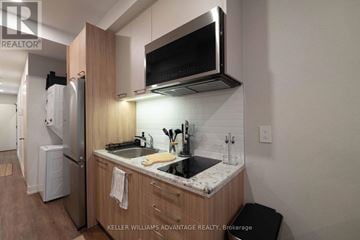 Toronto (Kensington-Chinatown) apartment for rent - A modern kitchen with a refrigerator, microwave, and stove top oven.