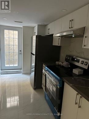 Vaughan (West Woodbridge) apartment for rent - A kitchen with a black fridge and white cabinets.