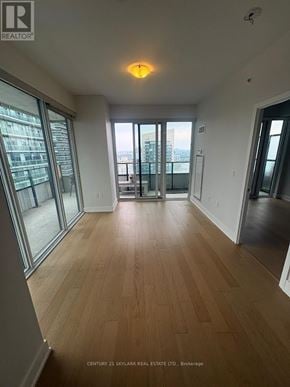 Toronto (Mimico) condo for rent - A spacious room with wooden flooring and large windows.
