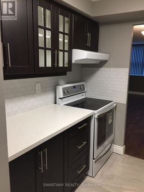 Brampton (Queen Street Corridor) condo for rent - A kitchen with a white counter top and black cabinets.