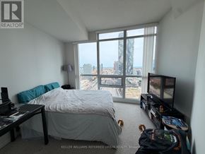 Toronto (Waterfront Communities) condo for rent - A bedroom with a large bed and a view of the city.
