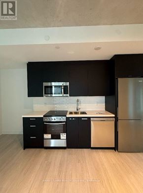 Toronto (Moss Park) condo for rent - A modern kitchen with black cabinets and stainless steel appliances.