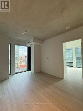 Toronto (Moss Park) condo for rent - A room with a wooden floor and a sliding glass door.