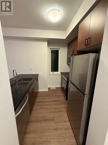 Brantford townhouse for rent - A kitchen with a refrigerator, sink, and cabinets.