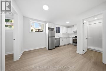 St. Catharines (Downtown) multi-family for rent - A spacious kitchen with white cabinets and a refrigerator.