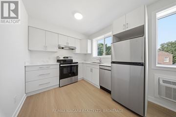 St. Catharines (Downtown) multi-family for rent - A kitchen with white cabinets and a stainless steel refrigerator.