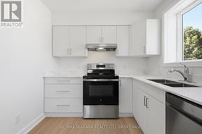 St. Catharines (Downtown) multi-family for rent - A white kitchen with a black dishwasher and stove top.