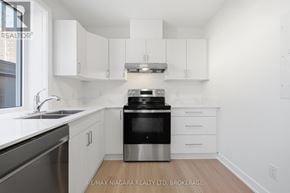 St. Catharines (Downtown) multi-family for rent - A kitchen with white cabinets and a black stove top oven.
