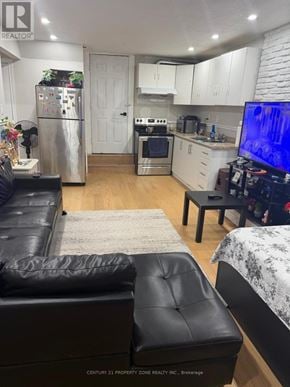 Brampton (Madoc) apartment for rent - A black leather couch sits in a kitchen with white cabinets and a refrigerator.
