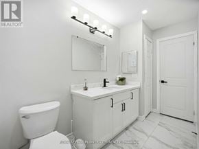 Brampton (Madoc) apartment for rent - A white bathroom with a toilet, sink, and mirror.